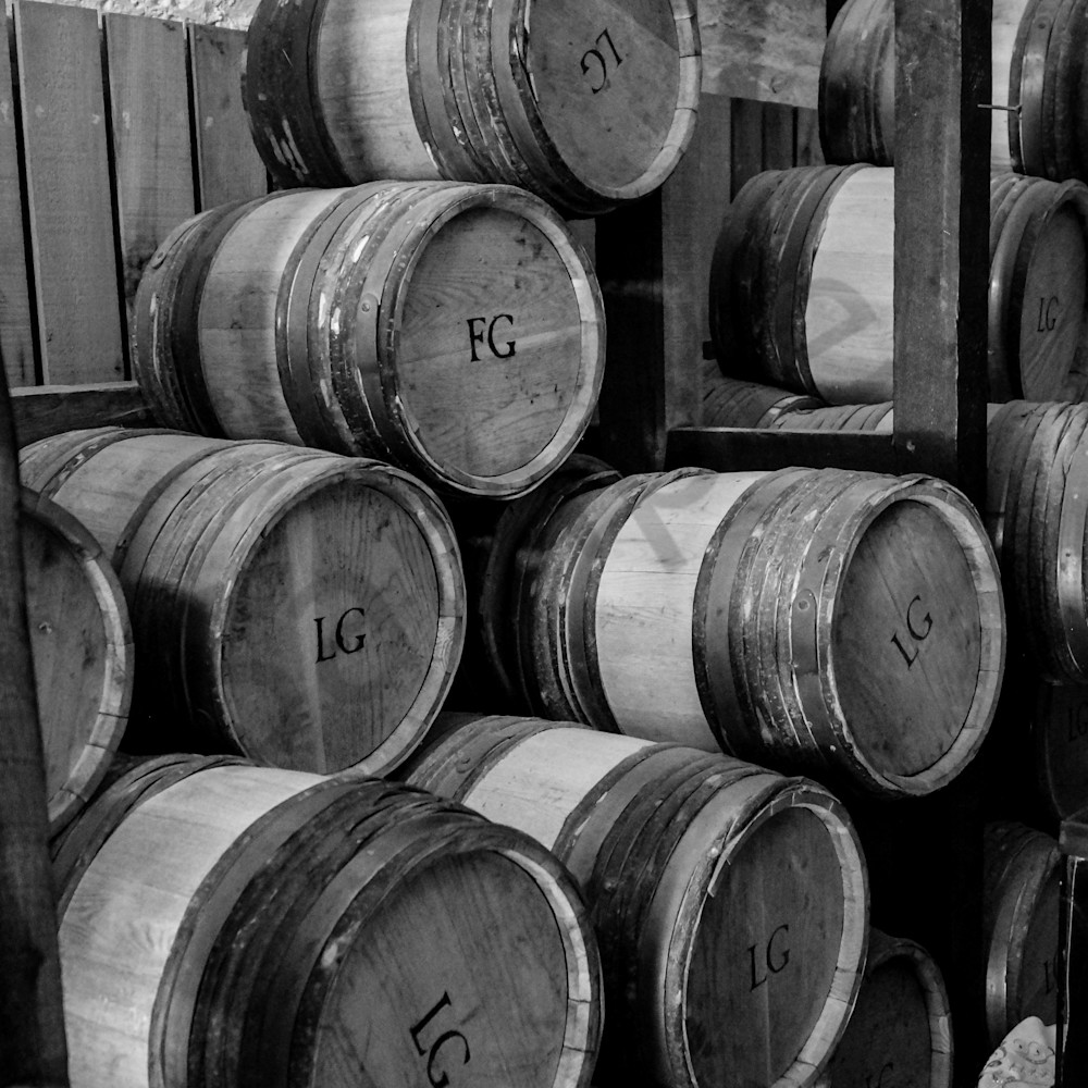 Black & white photograph of antique kegs, stacked at the magazine in
