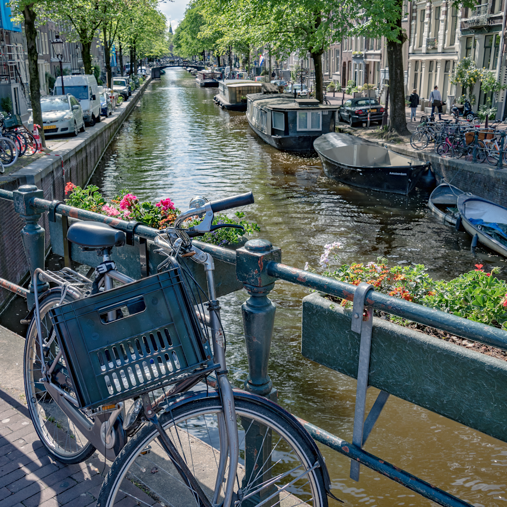 Lone bicycle with flower pots on bridge over canal. amsterdam netherlands atxplx
