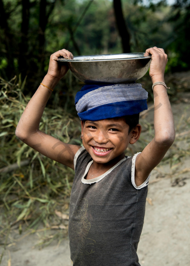 Smiling boy with metal bowl, and blue scarf on head