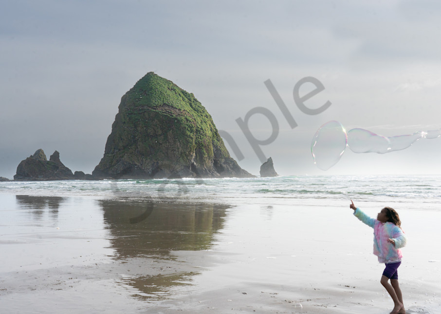 Little girl chases giant bubbles near Haystack Rock in photo for sale by Barb Gonzalez Photography.