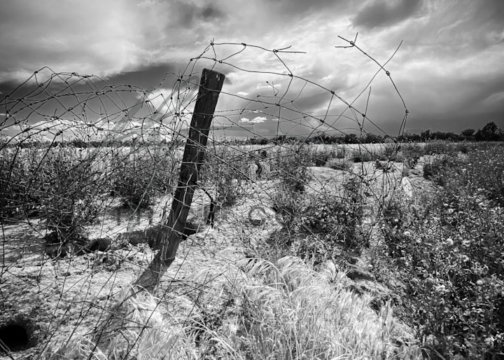 A barbed-wire post juts into the sky as a storm front passes through Yolo County, California.