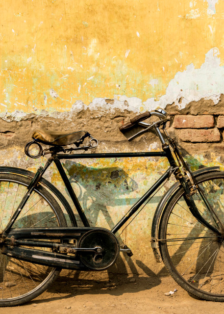 old bicycle by rustic yellow wall in art photograph