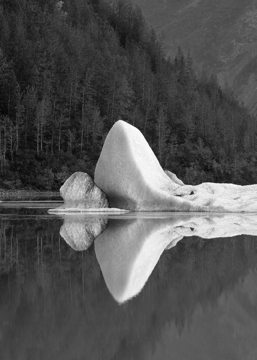 Iceberg from Valdez Glacier reflected in meltwater lake in Southcentral Alaska. Summer. Morning.