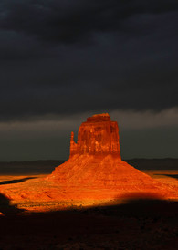 Monument Valley during a great sunset with dark clouds enhancing the Mittens.