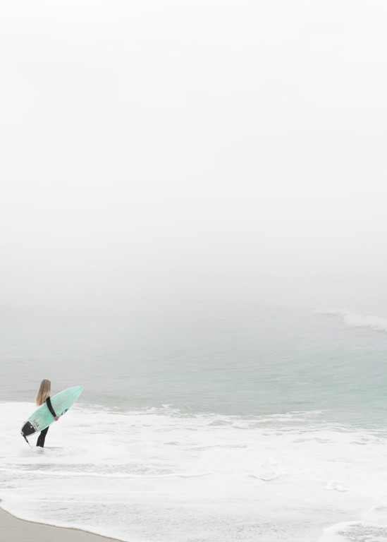 Surfer girl waiting for a wave on a foggy morning.