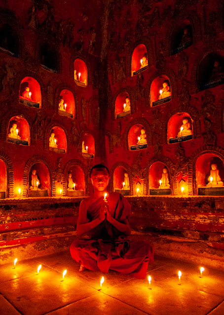 Prayer of a young Buddhist monk in a candle-lit temple, Myanmar.