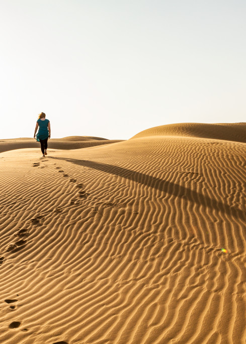 A woman walking on the sand dunes in the Thar Desert, Rajasthan, India. Near Rawala Resort.