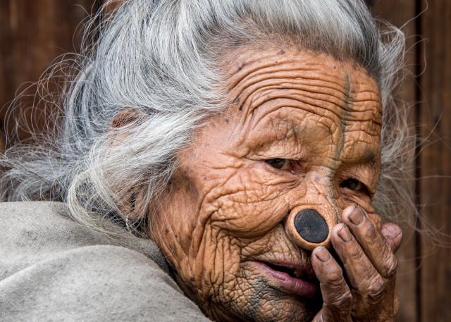 Portrait of old Apatani woman with face tattoo and nose plugs