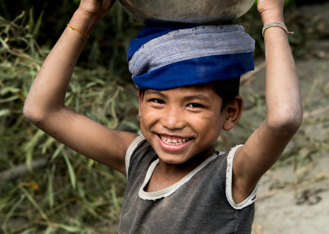 Smiling boy with metal bowl, and blue scarf on head