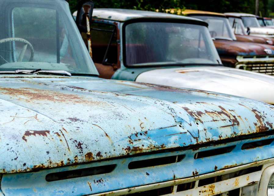 Row of classic cars, rusting in field, art photograph