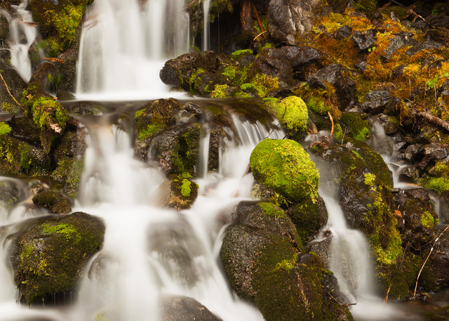 Cascade of water over boulders and moss from snow melt in spring from the Chugach Mountains bordering Eyak Lake in Cordova in Southcentral Alaska. Morning.