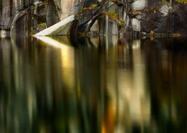 Reflections of stone quarry in stillness of pond