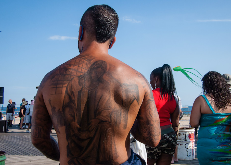 A tattoed man on the boardwalk at Coney Island.