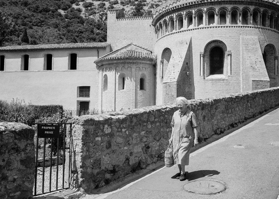 St-Guilhem-le-Desert, France, August 1998. A wopman walks by the abbey church of Gellone, The town is on the Chemin de St-Jacques, the pigriomage route to Santiago de Compostella. Part of the abbey cloister was moved to the U.S., and is part of the 