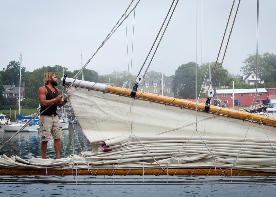 A deckhand furls the mainsail aboard the windjammer schooner Appledore II at the dock in Camden, Maine.