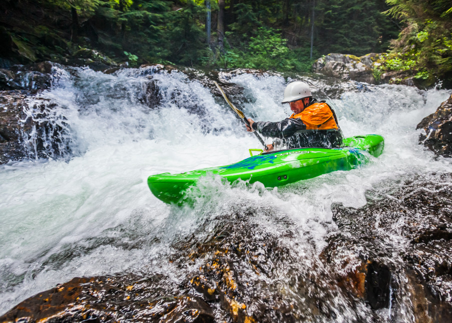 A man kayaking down a series of small waterfalls, Snoqualmie River (south fork), Washington, USA. Fall in the wall area.