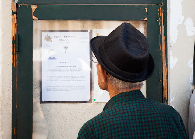 Elderly man reading the latest community obituary