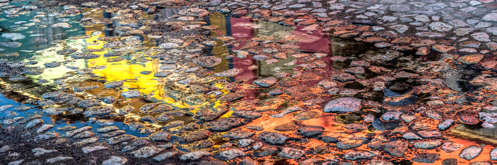 Colorful reflection in puddle on cobblestone street
