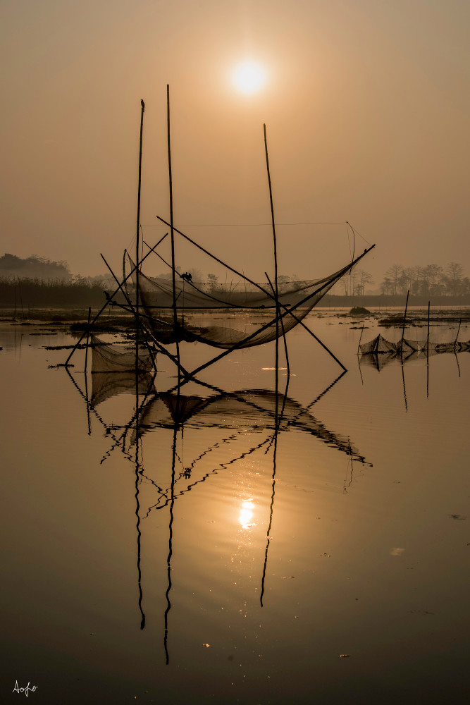 Fishing nets at sunrise reflecting in river water