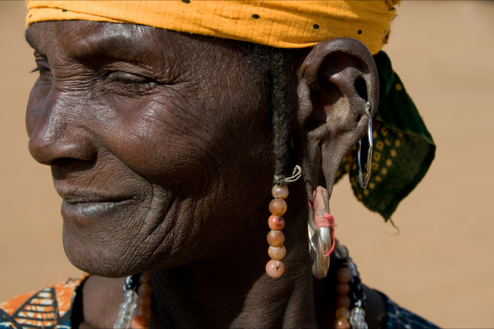A Fulani woman with big earring and yellow head cover, in fine art photograph