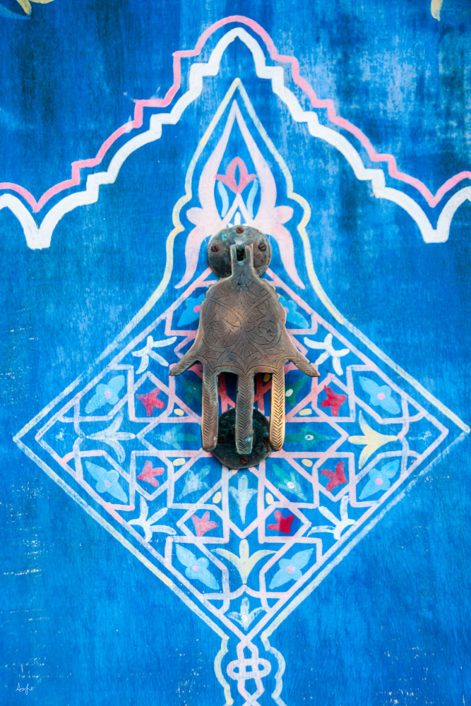 Photograph of a brass door knocker in shape of hand on colorful art door