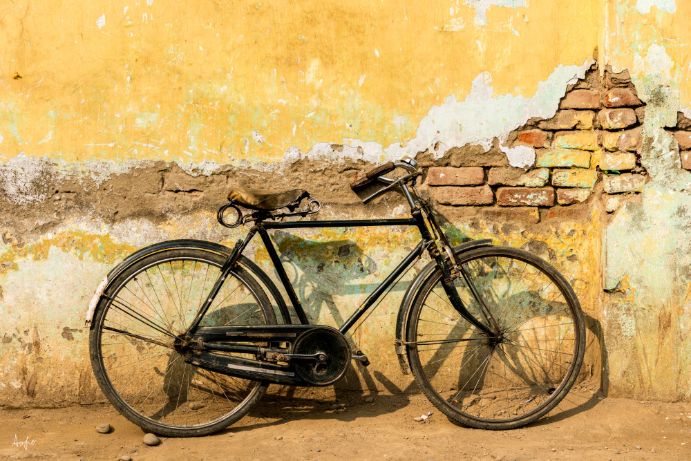 old bicycle by rustic yellow wall in art photograph