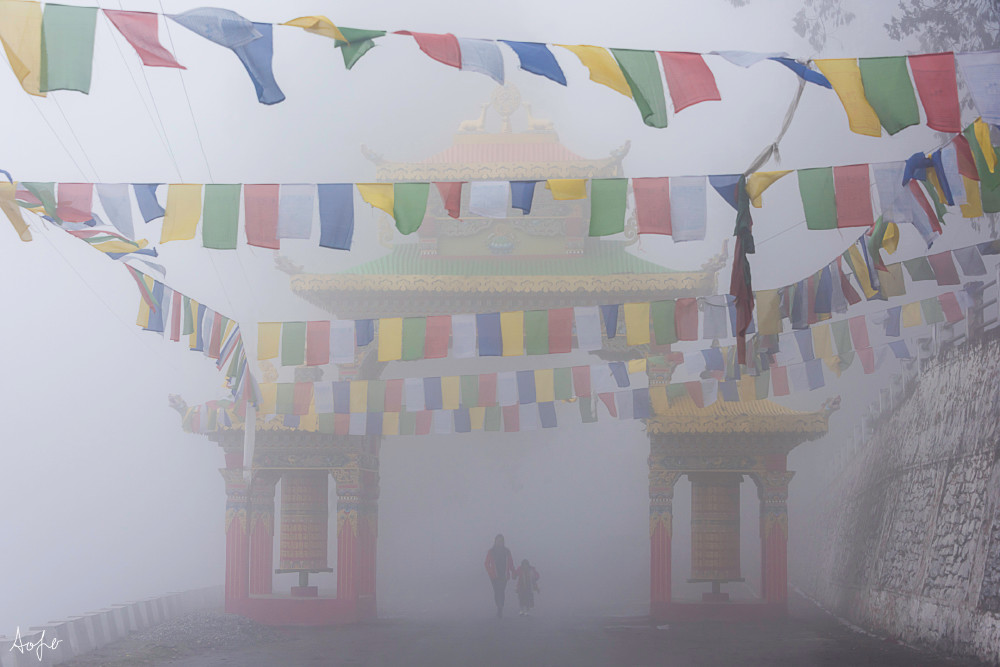 Fine art photograph of mother and child walking through fog under monastery gate