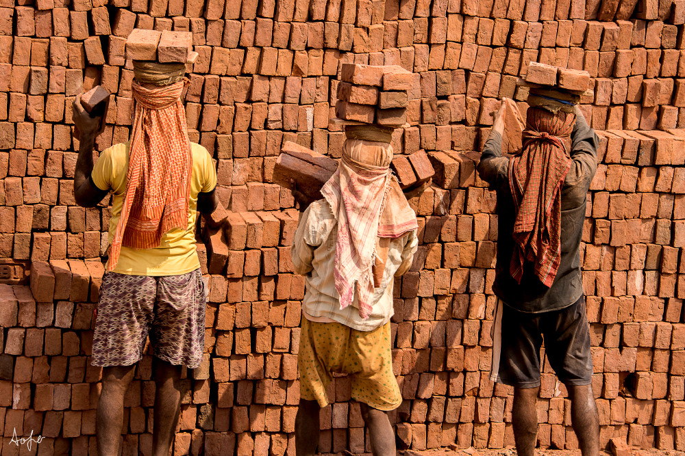 Three men carrying bricks on their head, from the back, in a fine art photograph print