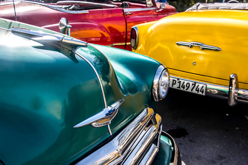 Fine art photograph of Red, yellow and green classic cars in partial view together