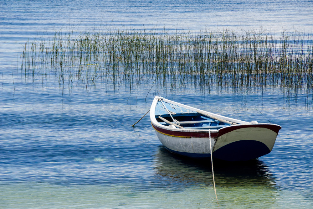 Fine art photograph of rowboat on blue water of Lake Titicaca
