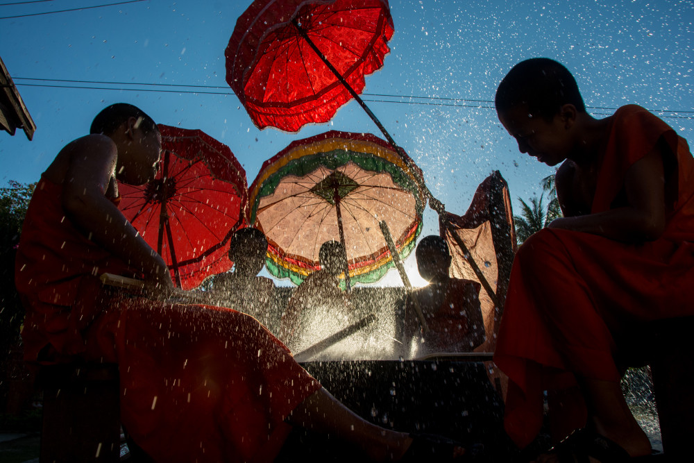 Monks beating a drum under red umbrellas