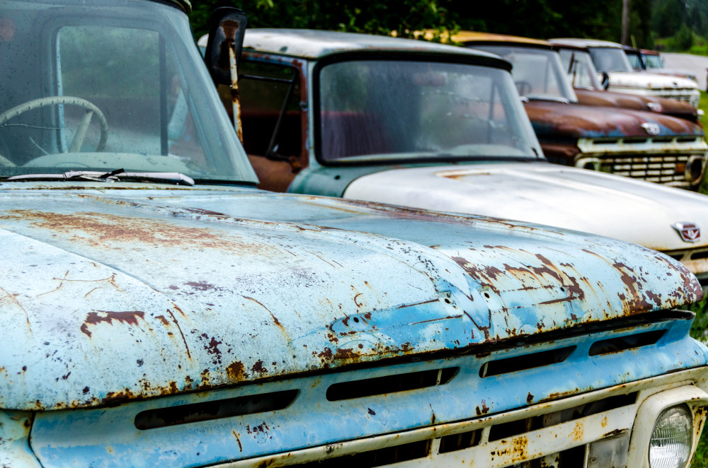 Row of classic cars, rusting in field, art photograph