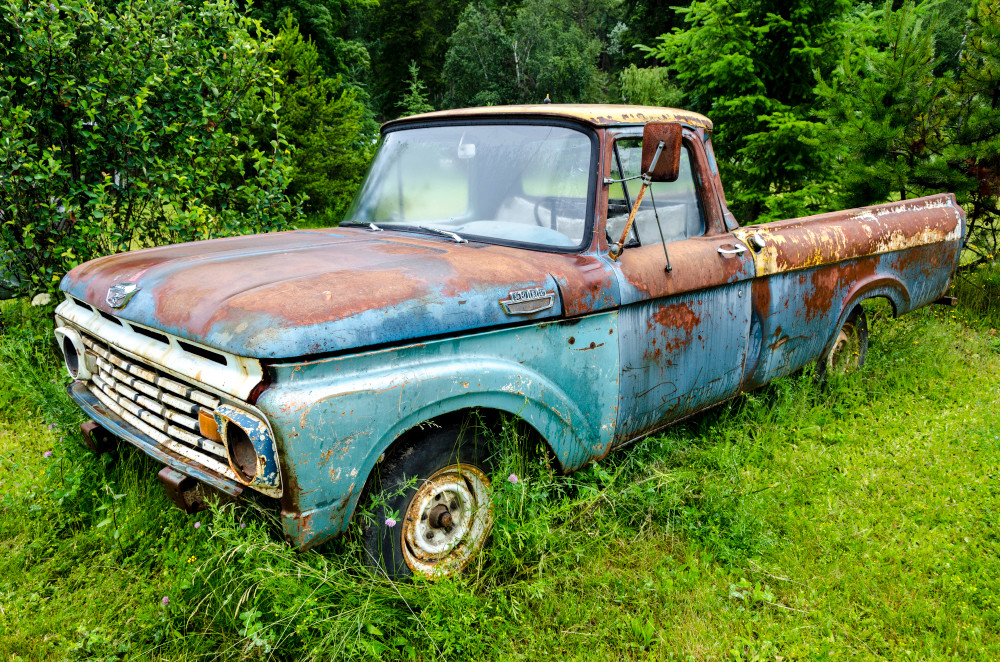 Blue rusting Ford classic pickup truck in field, art photograph