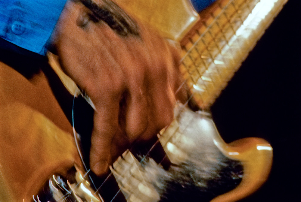 A Tattooed Hand Plays A Bass Guitar