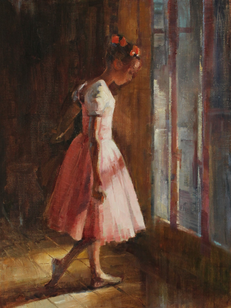 Adorable little ballerina in pink standing by a window.