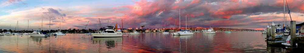 a panorama of boats in newport beach under red skies.