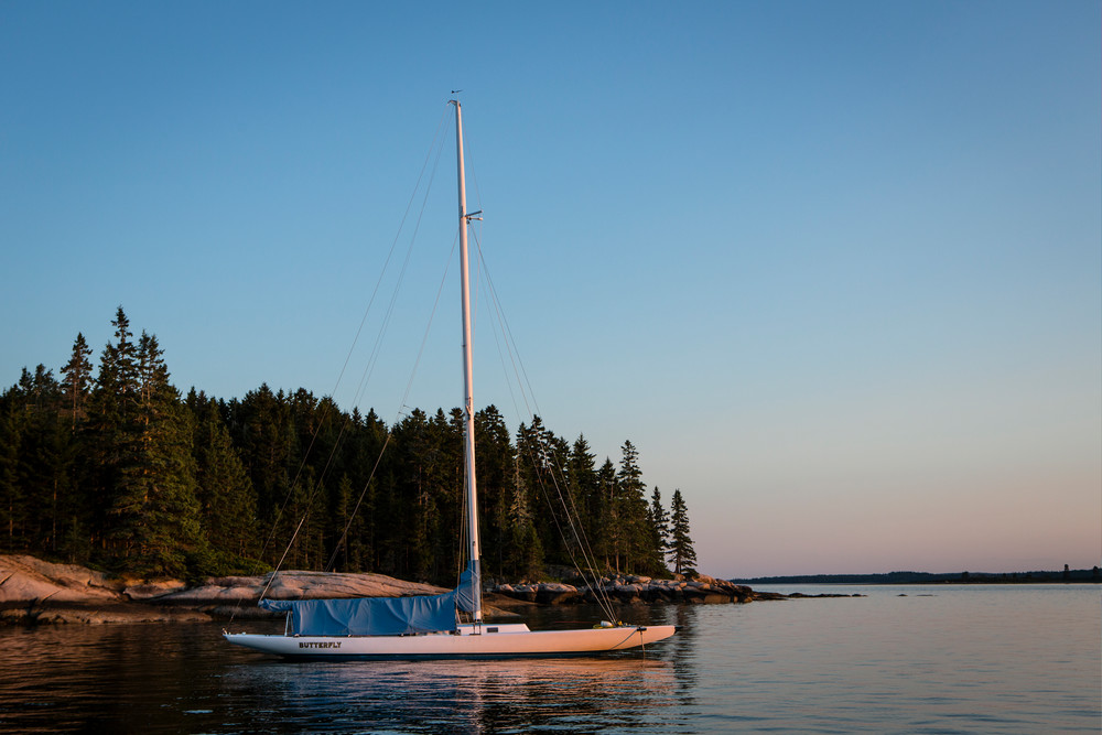 Center Harbor, Maine - 9 August 2014. Sloop Butterfly at anchor at sunset.