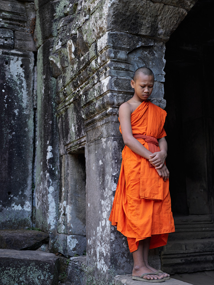 A limited edition framed print of a young devotee pausing amongst the ruins of a temple in Cambodia.