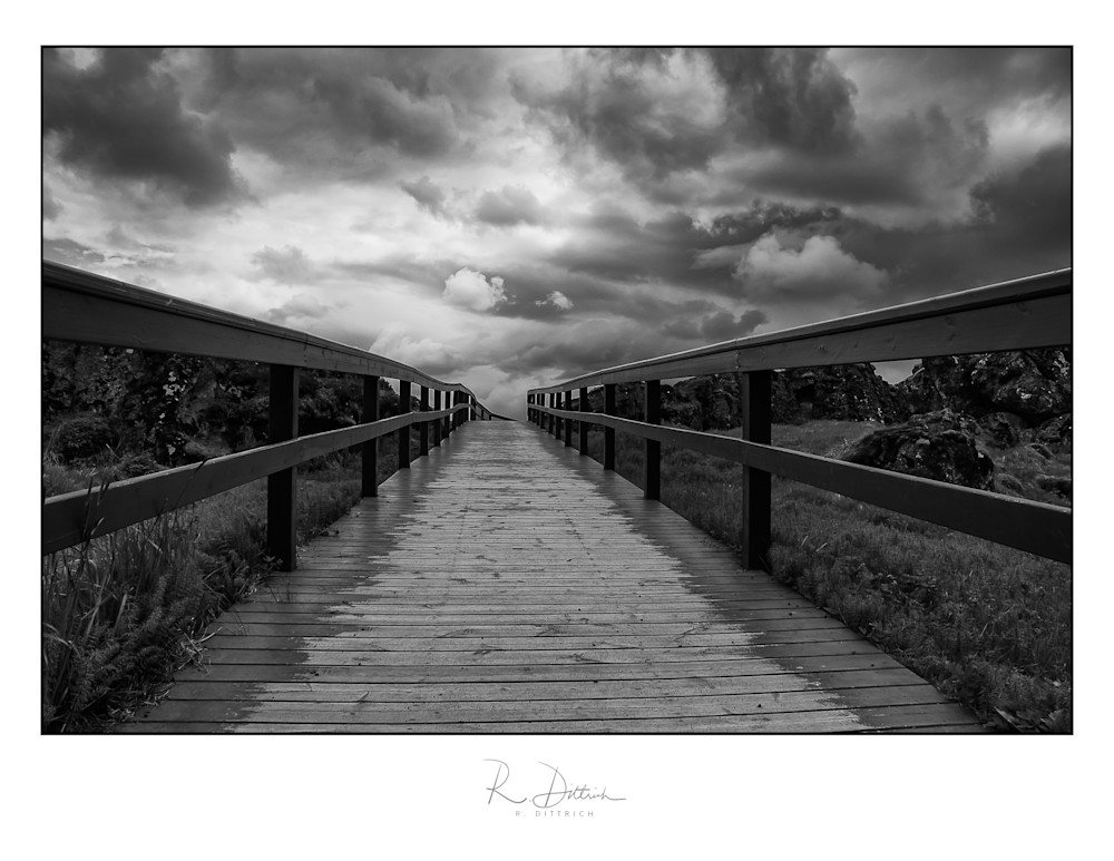 A black and white photograph of a bridge to the clouds