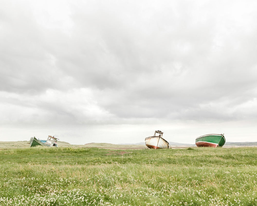 A fine art photograph of 3 old fishing boats in a field in ireland by Mia DelCasino