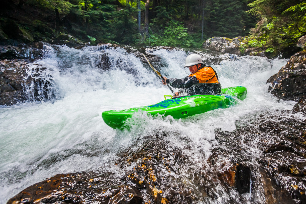 A man kayaking down a series of small waterfalls, Snoqualmie River (south fork), Washington, USA. Fall in the wall area.