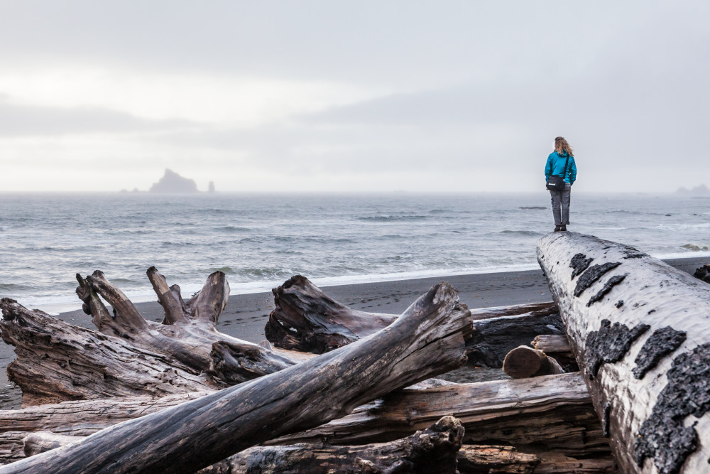 art photography prints for sale buy art online lone woman standing large driftwood log beach Pacific ocean, Rialto Beach Olympic national Park coast Washington