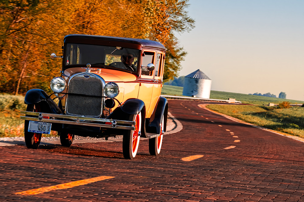 A timeless fine art photograph of a Model A Ford traveling The Alburn brick section of Route 66 in Illinois in The fall. 
