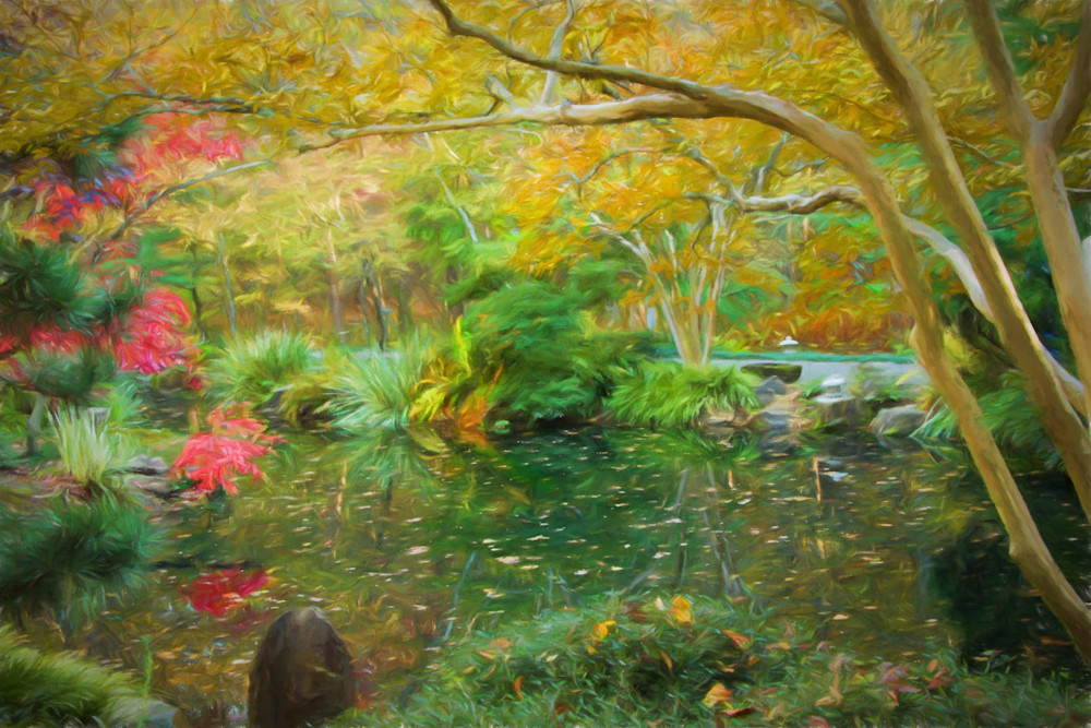 A fall scene with leaves scattered in a pond surrounded by fall foliage.
