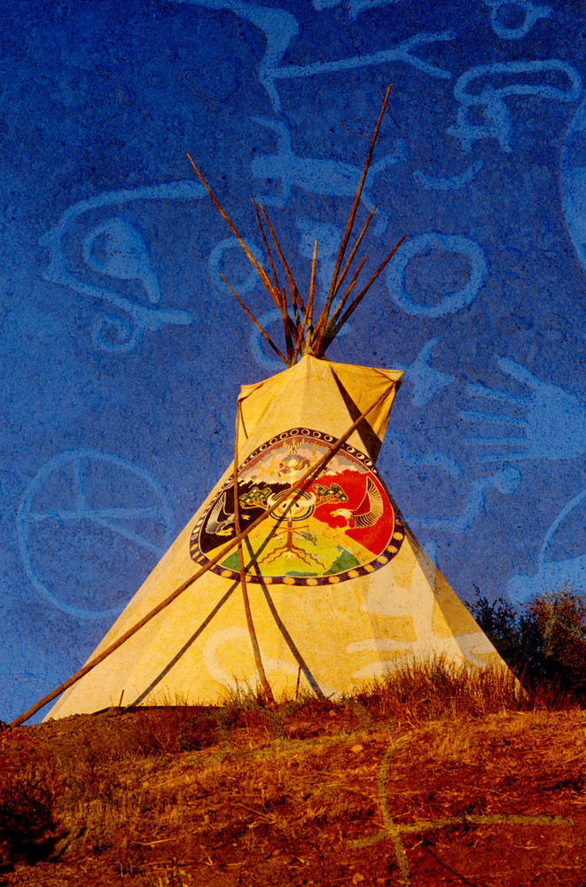 Composite image of a teepee silhouetted at dusk and Indian petroglyphs in the sky