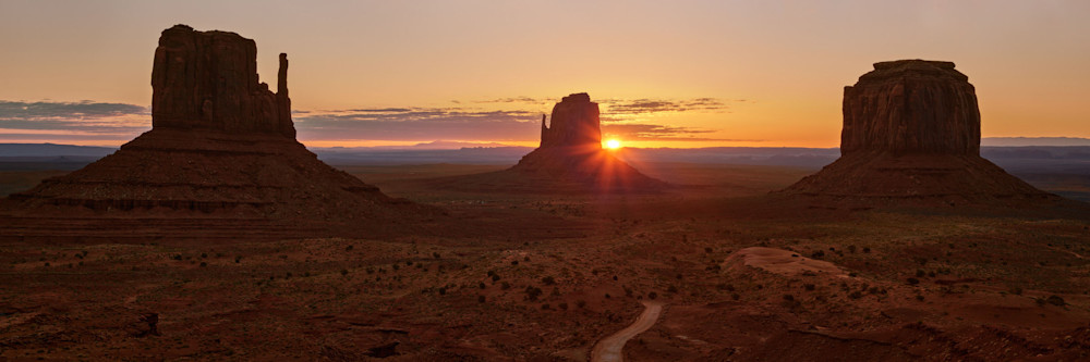 A spectacular sunrise photograph of the world famous Monument Valley Mittens and Merrick Buttes with a sunburst