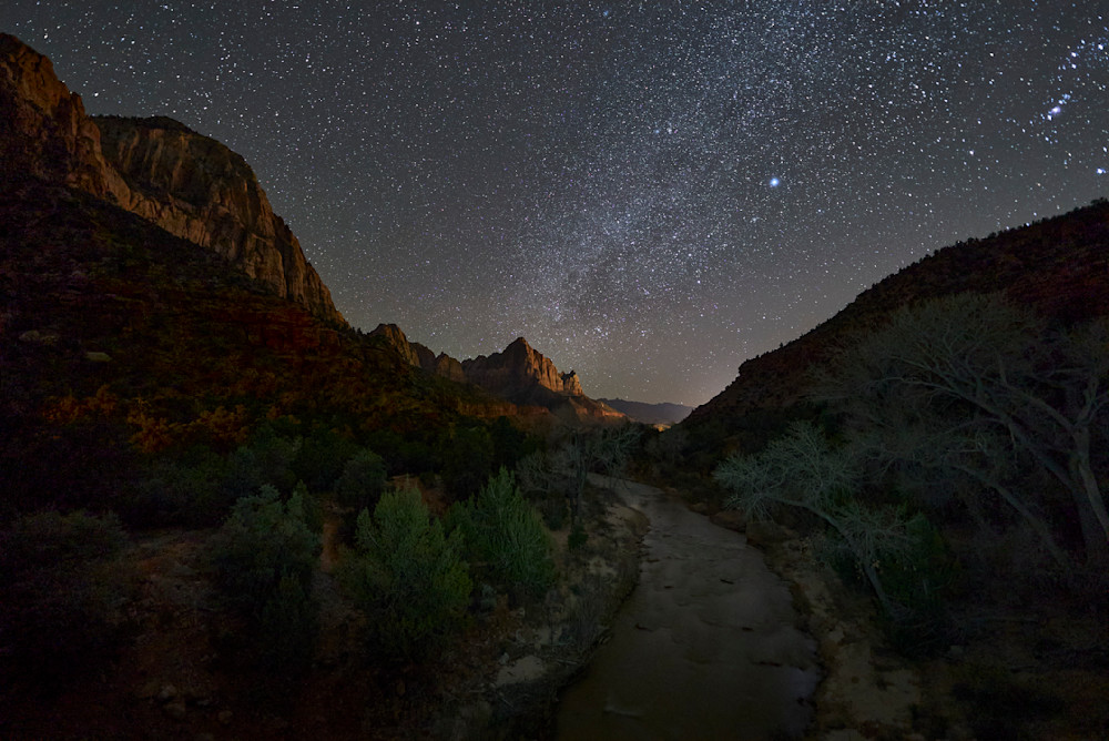 A painterly night-sky photograph of the Virgin River flowing into the Watchman with the milky-way above.