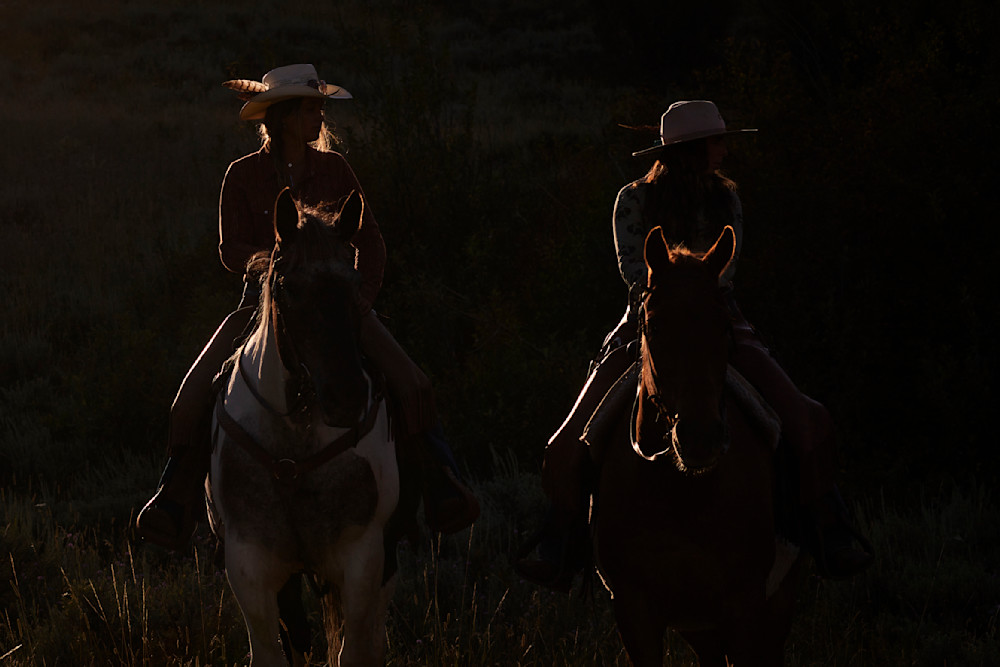 A hauntingly beautiful silhouette of two women on horseback.