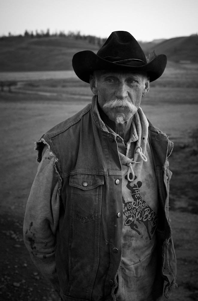 A black-and-white portrait photograph of an authentic cowboy with the open plains of Wyoming in the background.