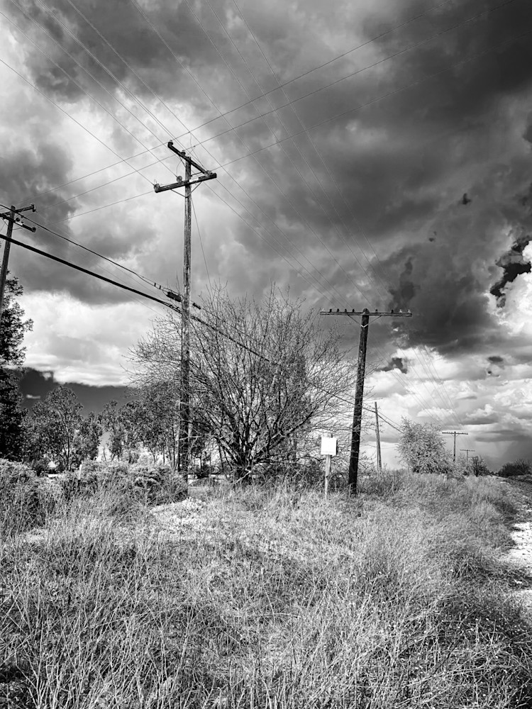 Trackside telephone poles and lines stand vigilant beneath storm clouds.